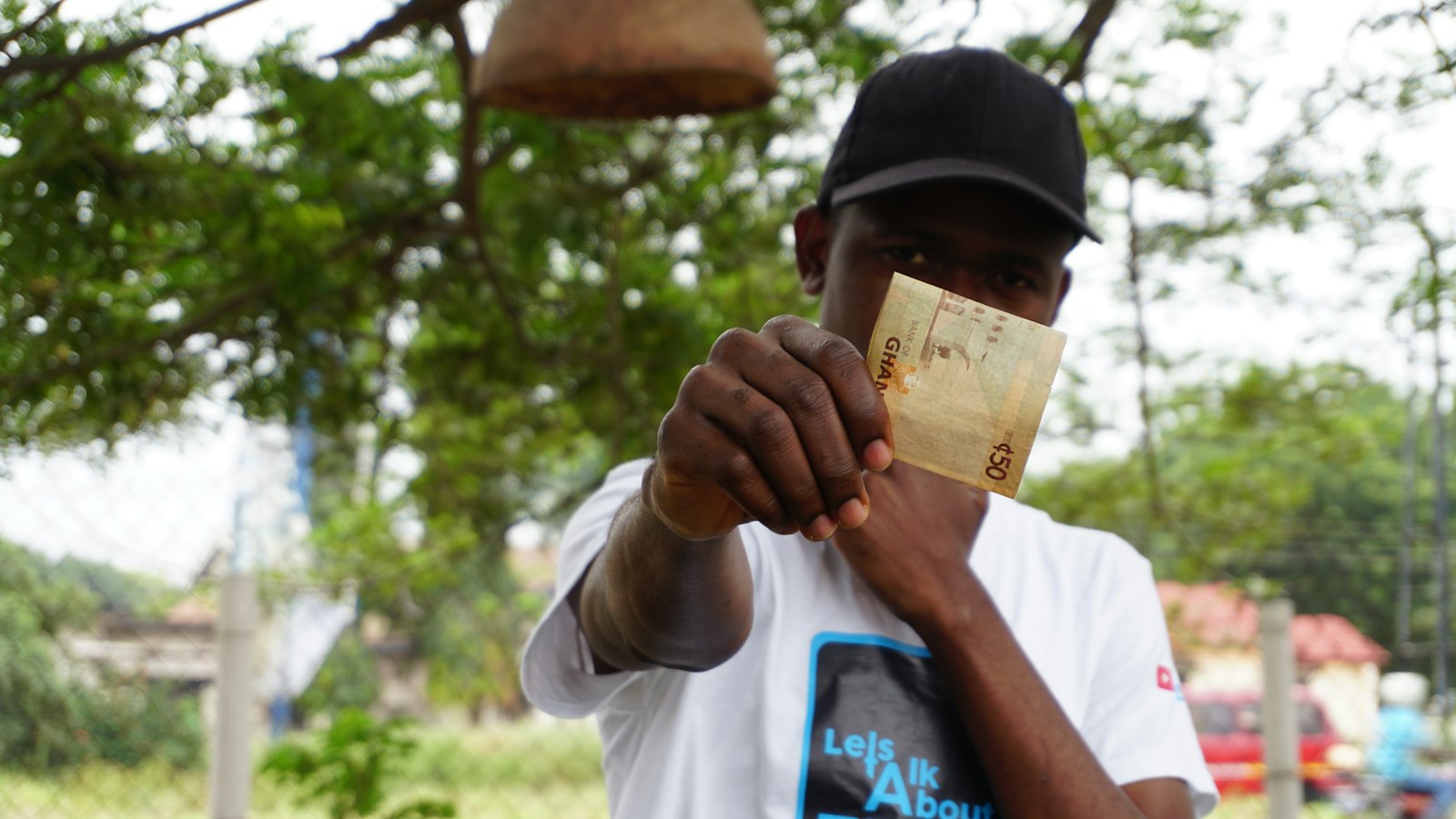A man in Ghana holding up a GH₵50 Bank of Ghana banknote